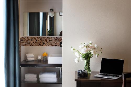 a room with a desk with a laptop and a vase of flowers at Hotel Corsignano in Pienza