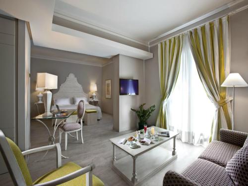 a hotel room with a living area with a couch and a table at Grand Hotel Baia Verde in Catania
