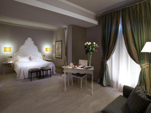a hotel room with a large bed and a table at Grand Hotel Baia Verde in Catania