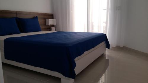 1 dormitorio con cama con sábanas azules y ventana en appart luxueux pieds dans l'eau, en Port El Kantaoui