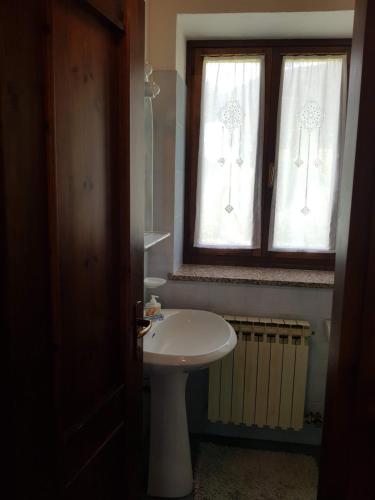 bagno con lavandino bianco e finestra di L'Atelier du Temps - Maison Quaglia a La Salle