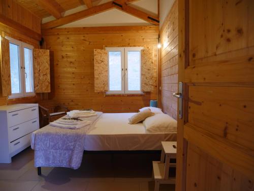 een slaapkamer met een bed in een houten hut bij Camping Fiori di Noto in Noto