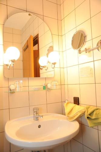 ein Bad mit einem Waschbecken und einem Spiegel in der Unterkunft Pension Erlaa in Wien