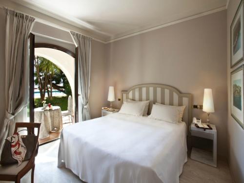 a bedroom with a white bed and a large window at Grand Hotel Baia Verde in Catania