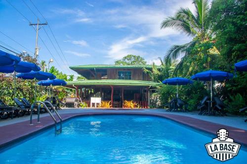 a swimming pool in front of a house with blue umbrellas at Hotel La Isla Inn in Puerto Viejo