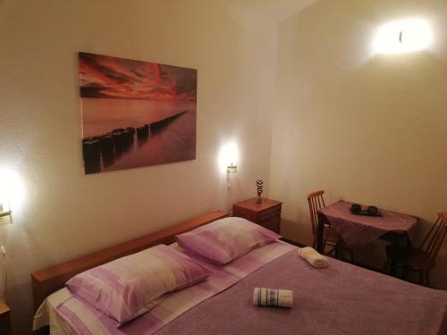 een slaapkamer met een bed met roze kussens en een tafel bij Vacation Home Mirjana in Seget Vranjica