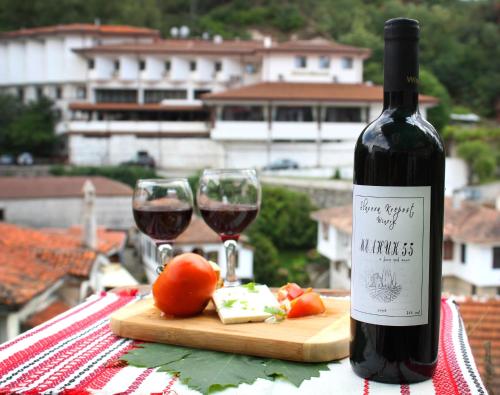 a bottle of wine next to two glasses of red wine at Hotel Slavova Krepost in Melnik