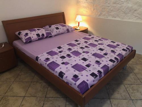 een slaapkamer met een bed met een paarse sprei en kussens bij Apartmani Pavicevic in Podgorica