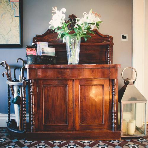 a vase of flowers on top of a wooden cabinet at Rum Doodle, Windermere B&B in Windermere