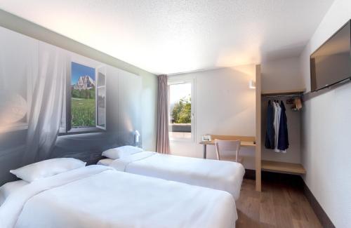 a hotel room with two beds and a window at B&B HOTEL CHAMBERY La Cassine in Chambéry