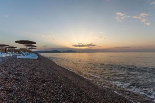 a beach with umbrellas and chairs and the ocean at Eco Beach And Magic Garden Hotel in Gennadi