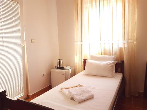 a bedroom with a bed with white sheets and a window at Apartments and Rooms Lijesevic in Budva