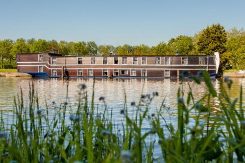 a house boat on the water with trees in the background at Boat Hotel De Barge in Bruges