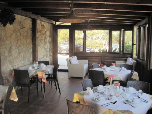 un restaurante con mesas y sillas blancas y ventanas en B&B Villa Giusy, en Siracusa