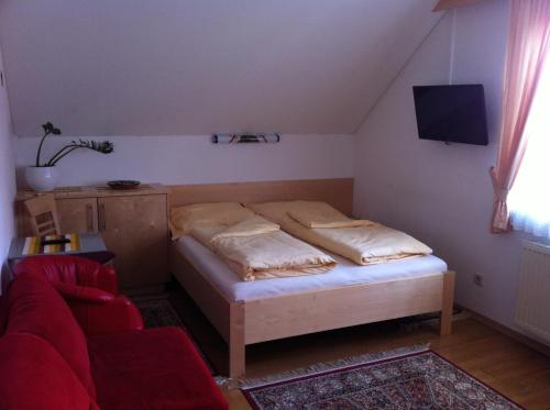 a small bedroom with a bed and a red couch at Gästehaus AIGMÜLLER in Bad Schallerbach