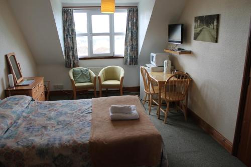 a hotel room with a bed and a table and chairs at Malin House Hotel in Saundersfoot