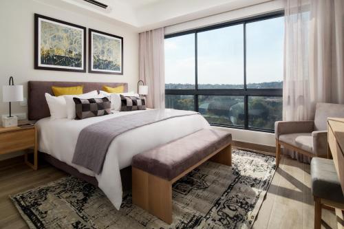 The Regency Apartment Hotel Menlyn في بريتوريا: غرفة نوم بسرير كبير ونافذة كبيرة