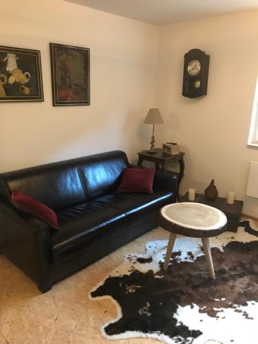 a living room with a black leather couch and a table at Blockhaus im Kuckuckswinkel in Schöna