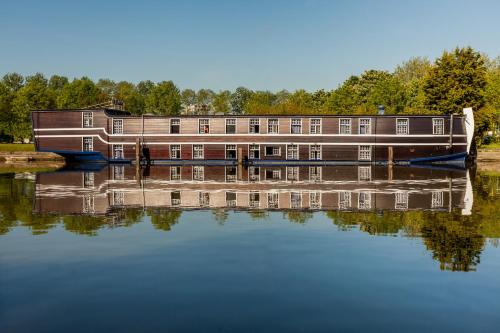 uma casa-barco num rio com o seu reflexo na água em Boat Hotel De Barge em Bruges