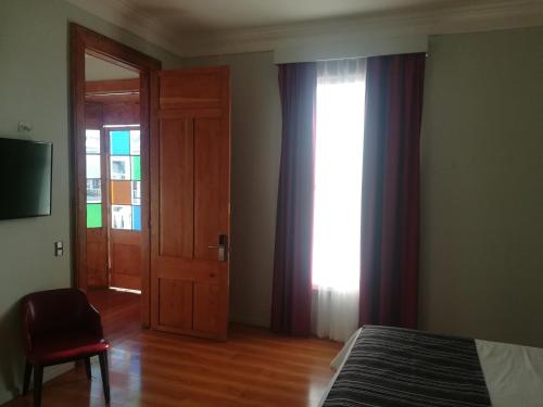 a bedroom with a bed and a door and a window at Hotel Baquedano Boulevard in Iquique