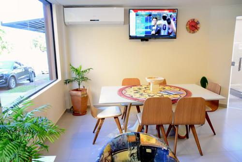Mandala Hotel في انكارناسيون: غرفة مع طاولة وكراسي وتلفزيون على الحائط