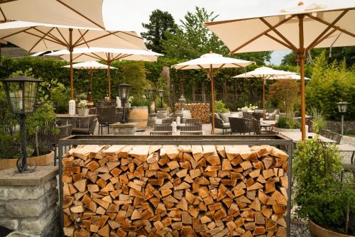 a pile of fire wood in a yard with umbrellas at Hotel-Restaurant Burgseeli in Goldswil