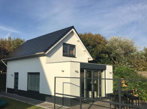 a small white house with a black roof at Salt Life Beachhouse in Noordwijk aan Zee