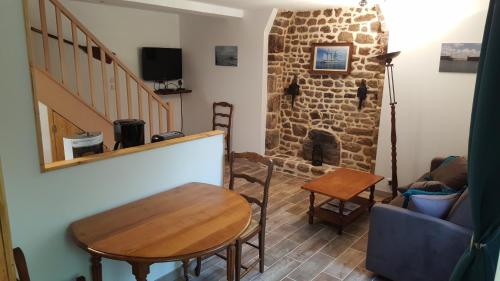 ein Wohnzimmer mit einem Tisch und einem Steinkamin in der Unterkunft Le Marite in Sartilly