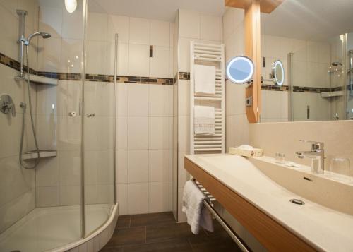 a bathroom with a shower and a sink and a tub at Hotel Hessenhof in Winterberg