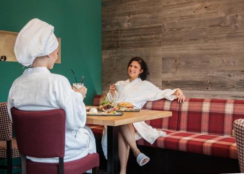 a woman sitting at a table in a restaurant with a child at Hotel Hessenhof in Winterberg