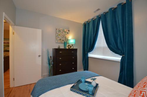 a bedroom with blue curtains and a bed and a dresser at The SoMa Furnished Residences in Hamilton