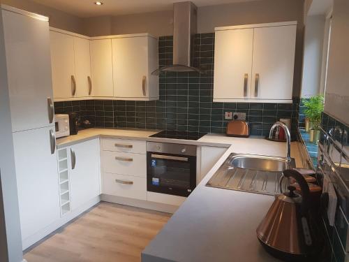 a kitchen with white cabinets and a sink at Spire View Townhouse in Ballycastle
