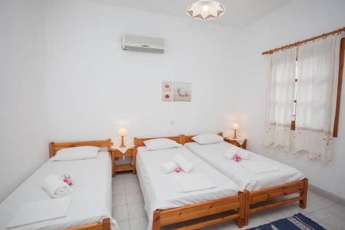 a bedroom with two beds and a window at Anestoula Rooms in Skala