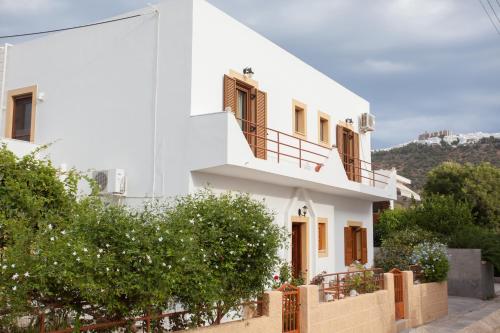 a white house with a fence in front of it at Anestoula Rooms in Skala