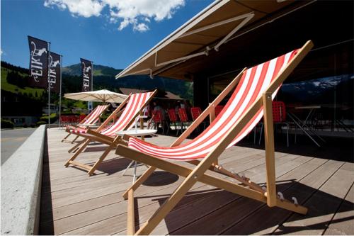 a row of lawn chairs sitting on a wooden deck at Chalet ELK Lenk in Lenk