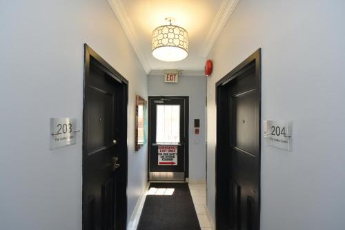 a hallway with two black doors and a window at The SoMa Furnished Residences in Hamilton