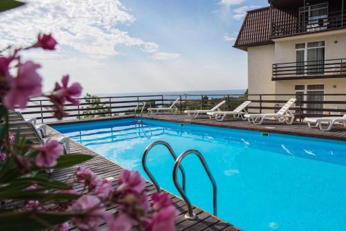 a swimming pool with chairs and the ocean in the background at Priliv Прилив in Gurzuf