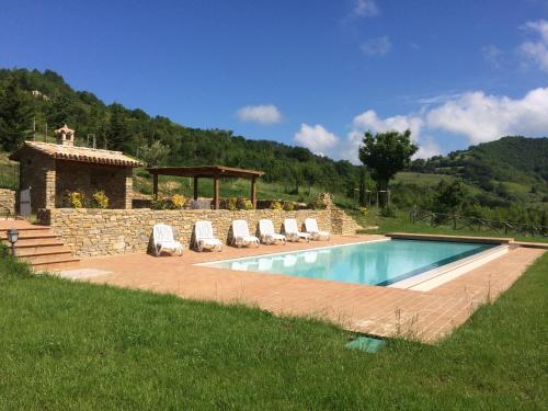 a swimming pool with chairs and a stone wall at Agriturismo Paradiso 44 in Assisi