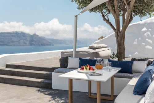 a white table with a bowl of fruit on a white couch at Chelidonia Luxury Suites in Oia