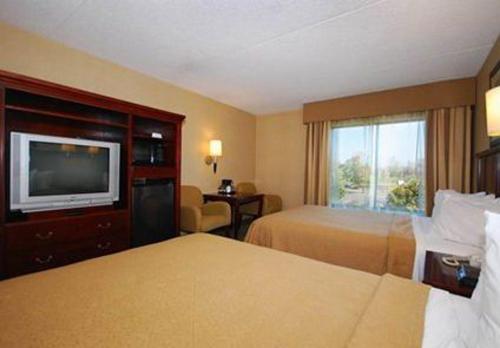 a hotel room with two beds and a flat screen tv at Quality Inn & Suites Bensalem in Bensalem