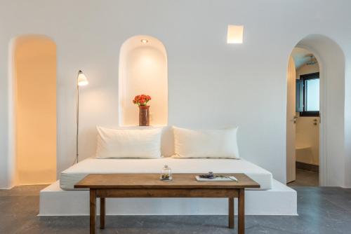 a bedroom with a white bed with a table at Chelidonia Luxury Suites in Oia
