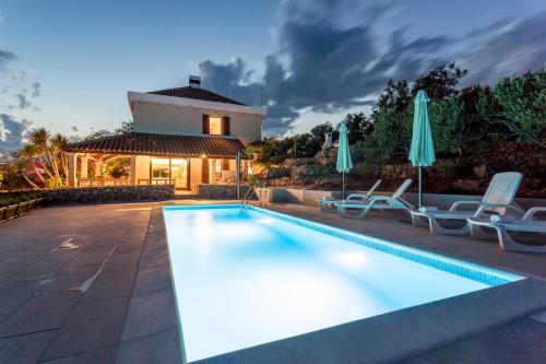 a swimming pool with chairs and umbrellas next to a house at Villa Fortica in Milna