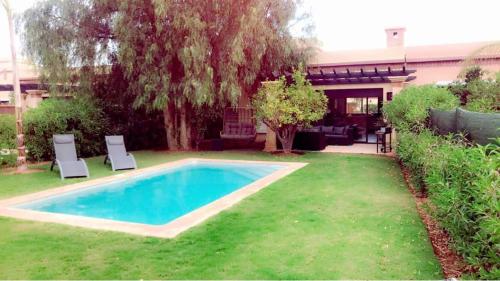 a swimming pool in a yard with two chairs at VILLA 186 AGADIR in Islane