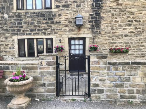 an old stone building with a black door and flowers at The Cottage, cosy 2 bedroom pet friendly perfect for contractors free secure parking,CCTV in Leeds