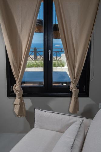 a window with a bed and a view of the ocean at IfestAu.4 Suites in Fira