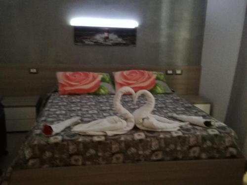 three swans are sitting on a bed with roses at Vianova Affittacamere in Giurdignano