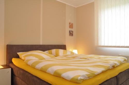 ein Bett mit gestreifter Decke in einem Schlafzimmer in der Unterkunft Austernbank in Wangerland