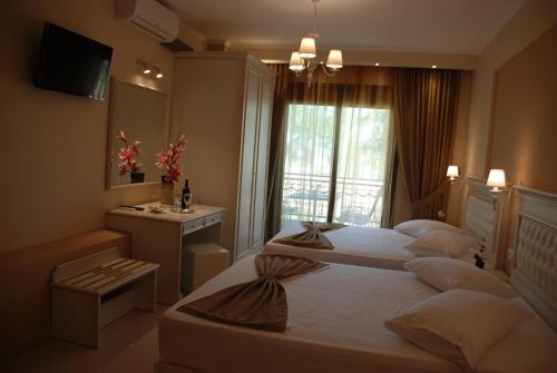 a hotel room with two beds and a window at Elxis Luxury Resort in Nea Vrasna
