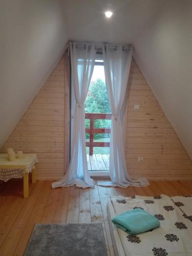 a room with a window with a bed and a table at Domek Letniskowy "Domek Lawendowy" in Pisz