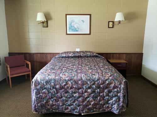 a hotel room with a bed and a chair at Spinning Wheel Motel in Baraboo